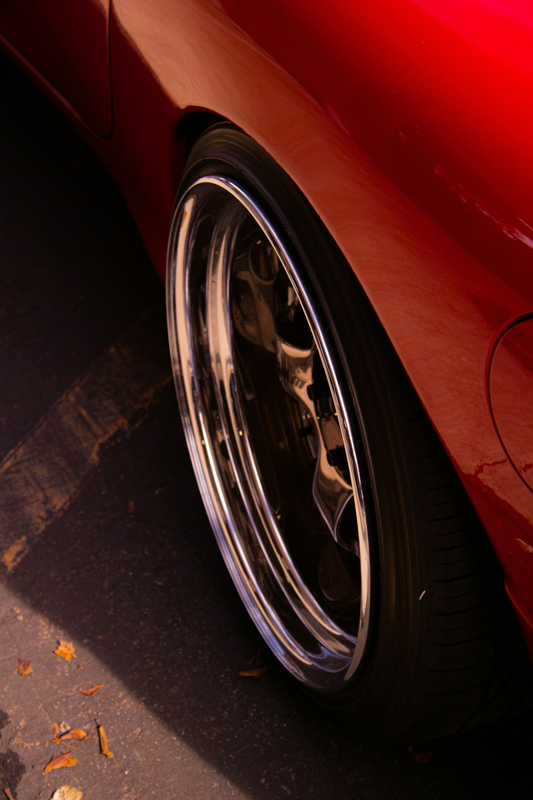Close-up of a deep, mirror-polished wheel lip tucked under red bodywork